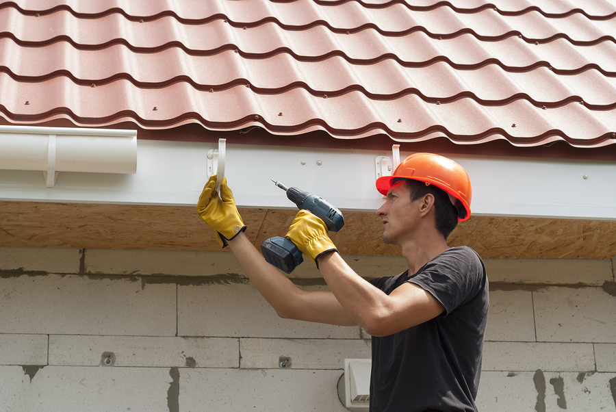 worker installs the gutter system on the roof